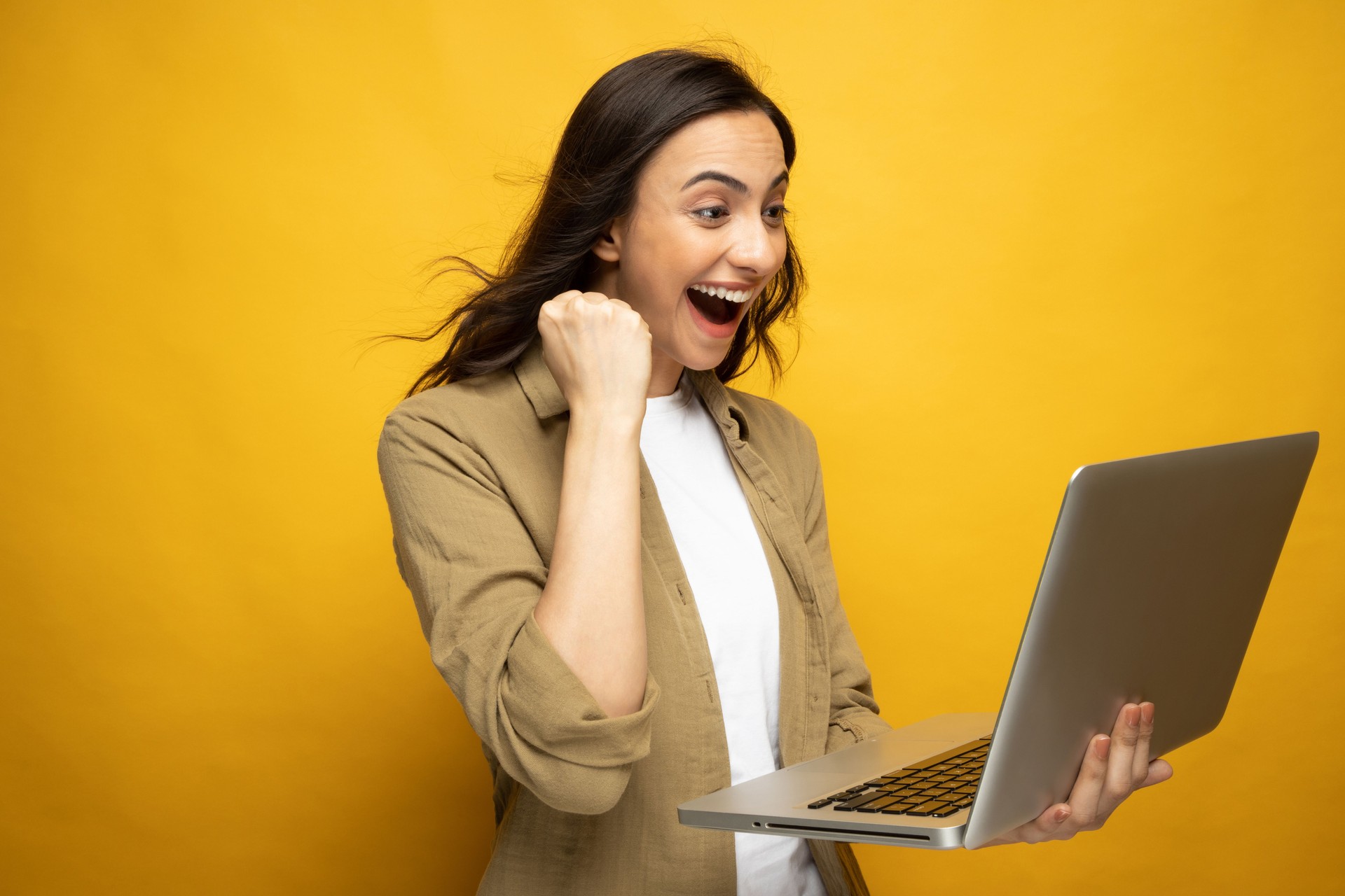 Portrait of young woman using laptop isolated yellow background stock photo